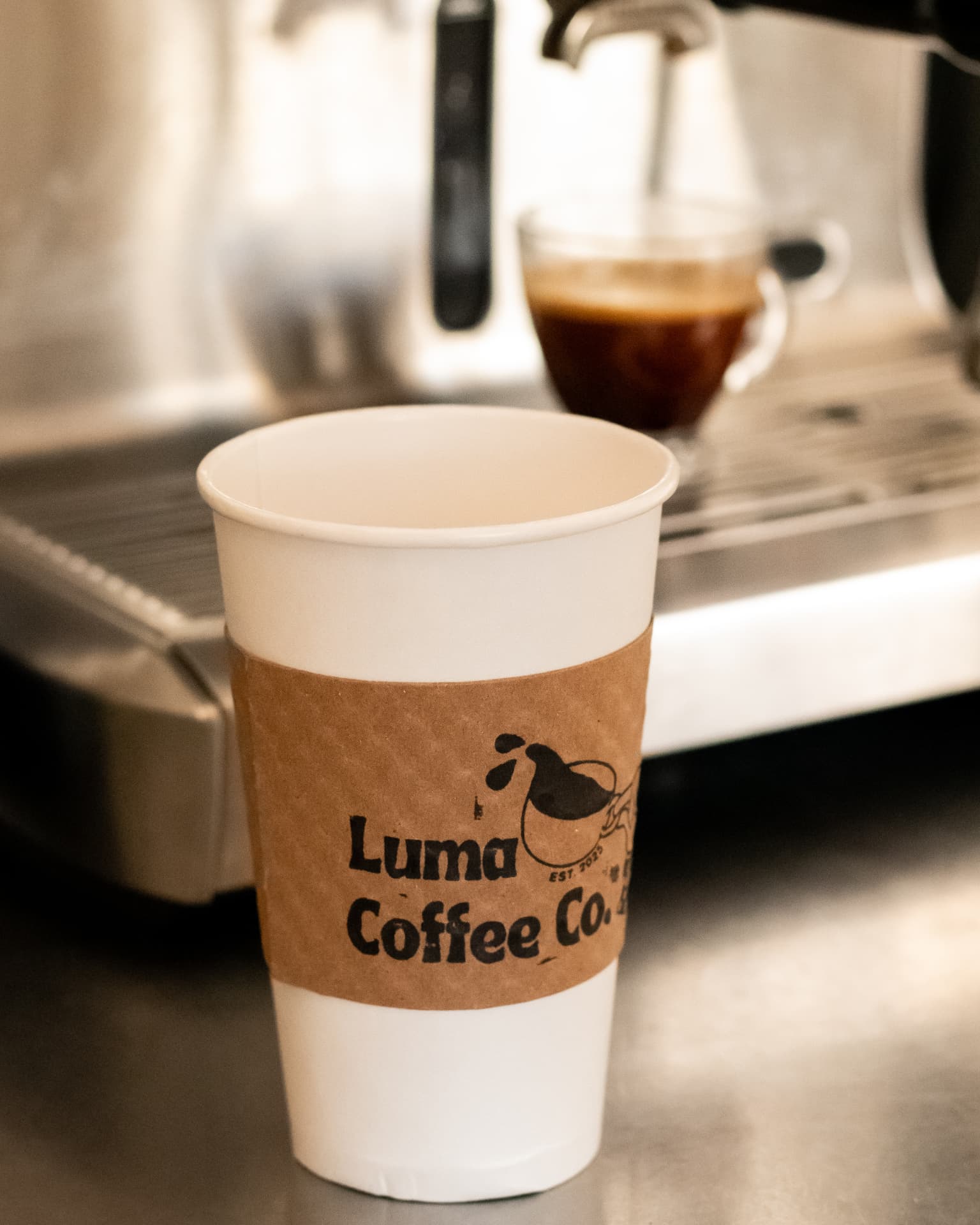A Luma Coffee Co. hot cup resting by the espresso machine