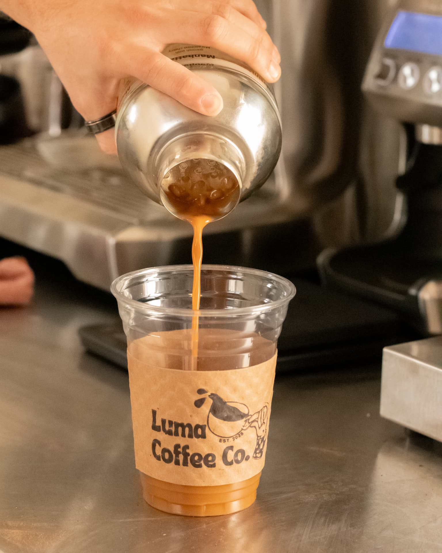 A shaken espresso being poured into a Luma Coffee Co. iced cup